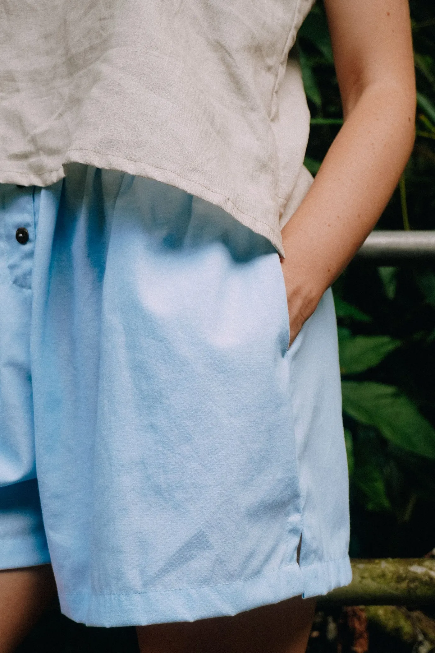 Detail of a relaxed shirt and blue shorts worn outdoors