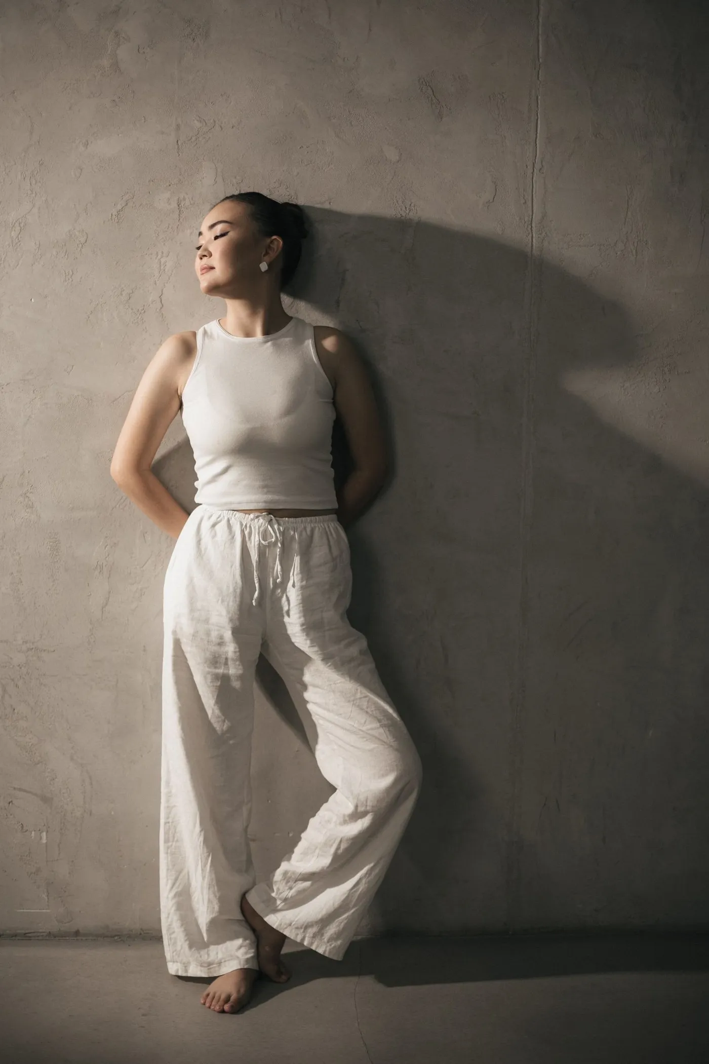 Woman pairing a white tank top with white linen trousers