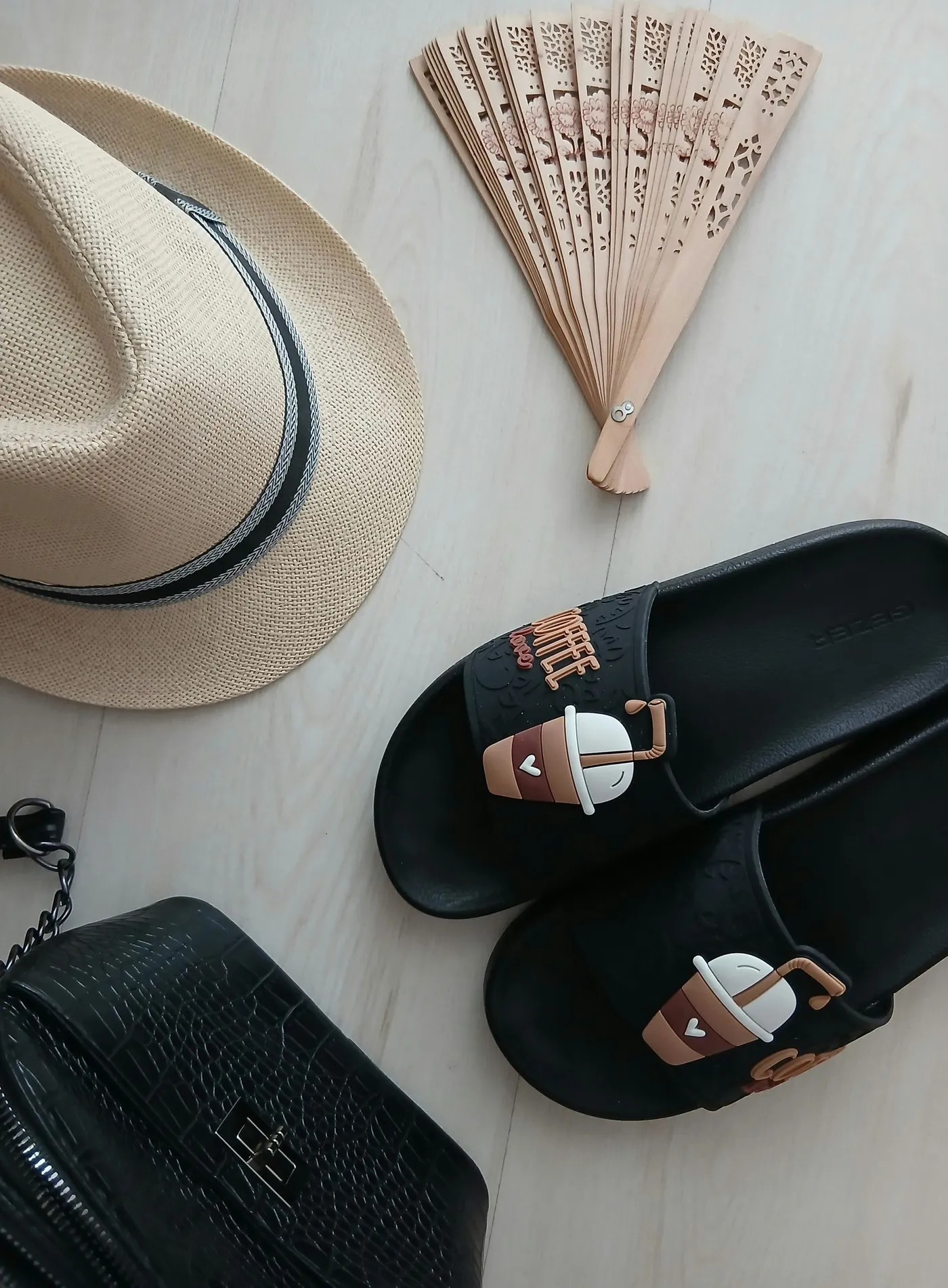 Summer hat, sandals, fan and bag arranged in a flat lay