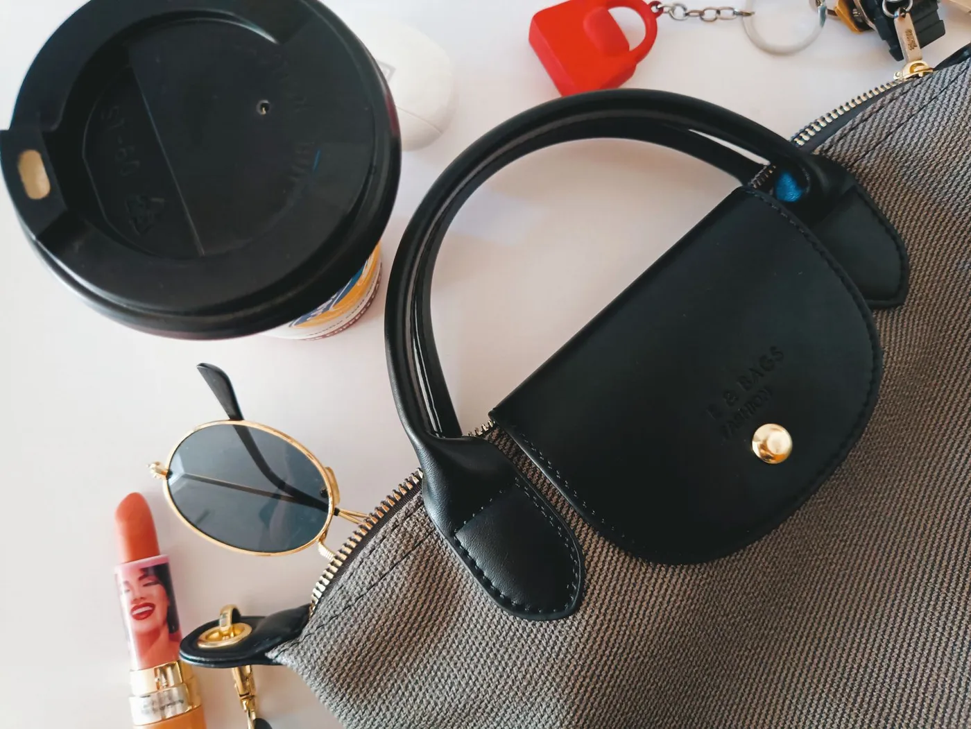 Handbag, sunglasses, lipstick and coffee arranged together