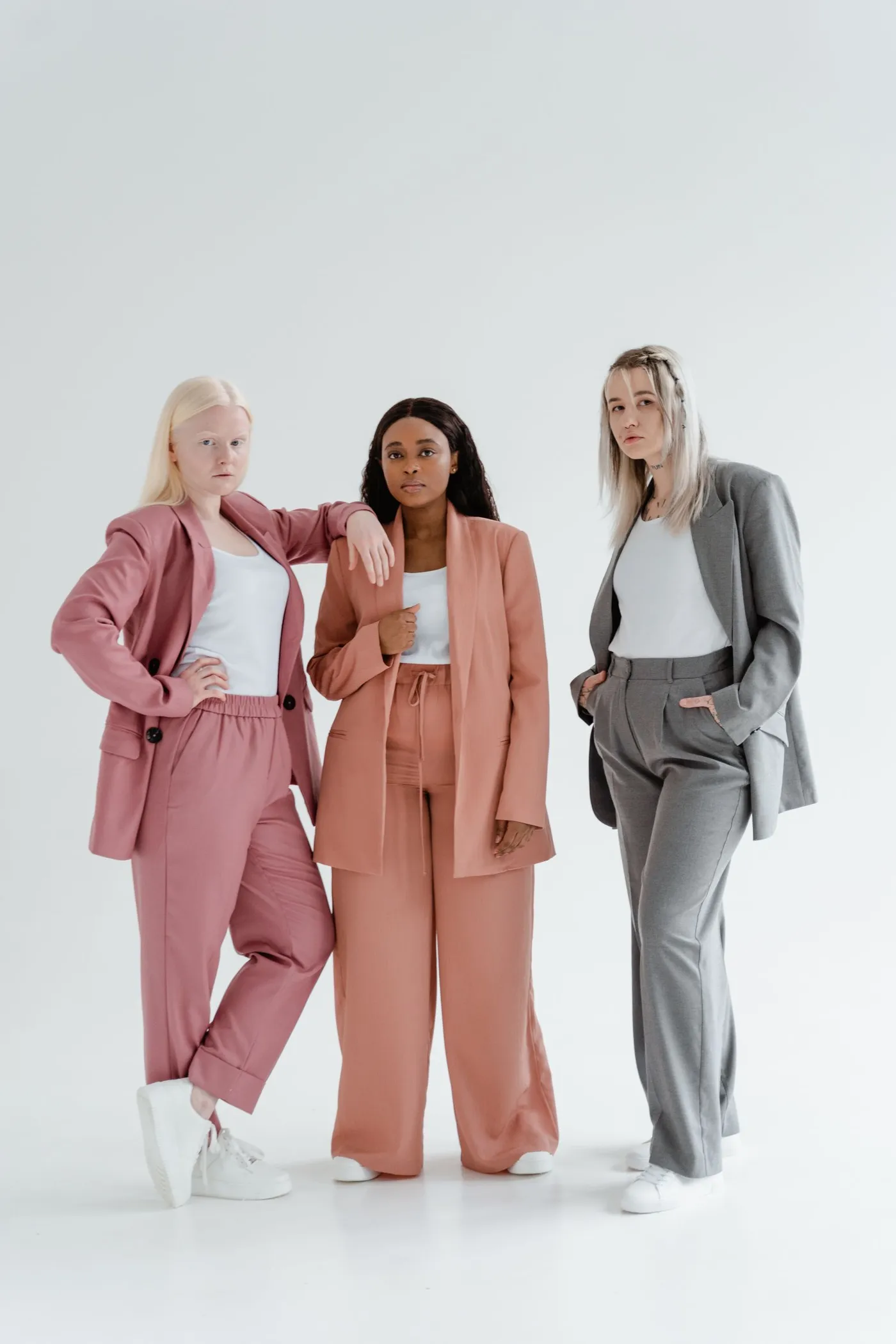 Three women wearing tailored suits in contrasting colours