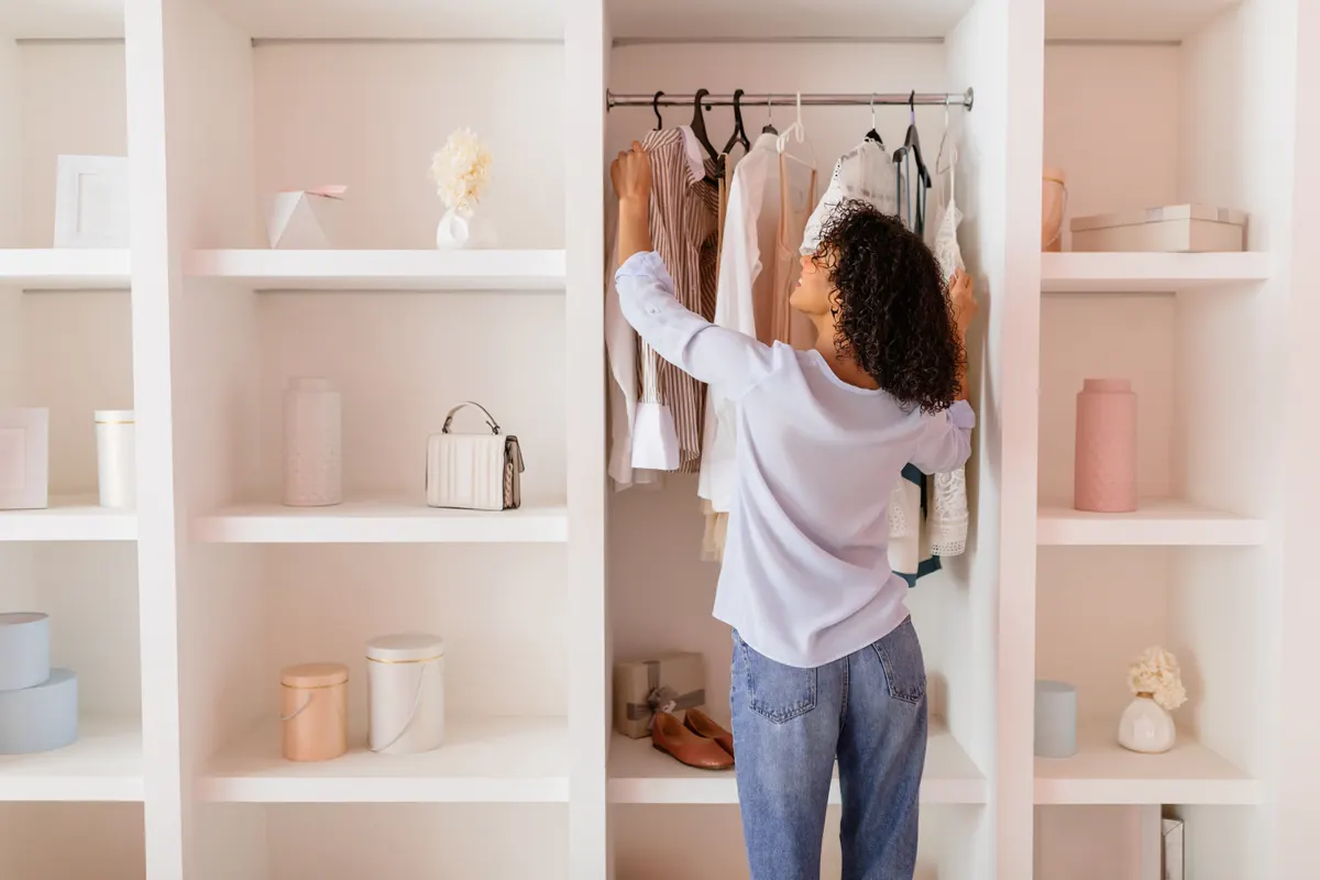 Woman organising clothes in a light coloured wardrobe