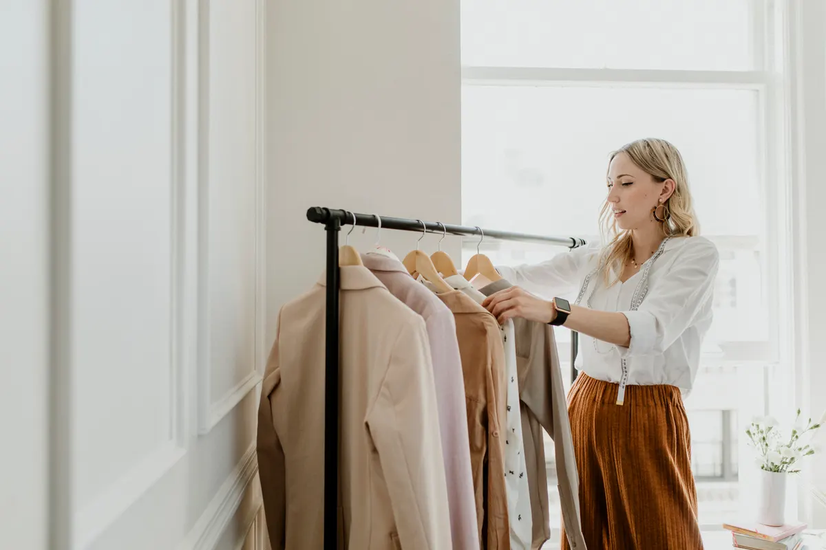 Woman selecting neutral garments from a clothes rail