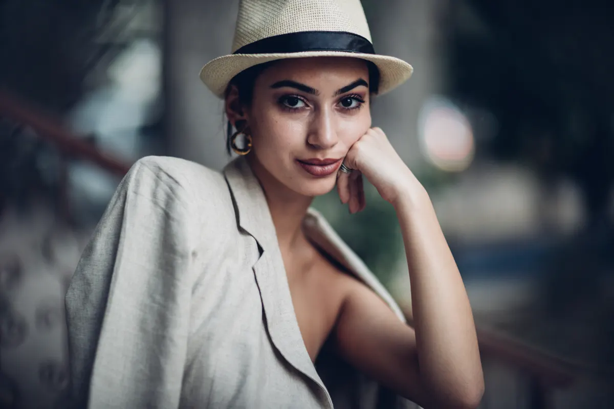 Woman combining a pale jacket with a structured hat