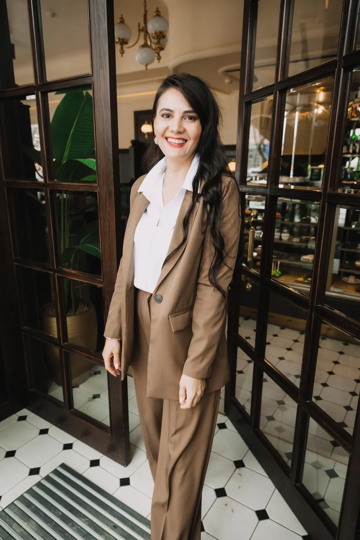 Woman layering a long brown coat over a light outfit