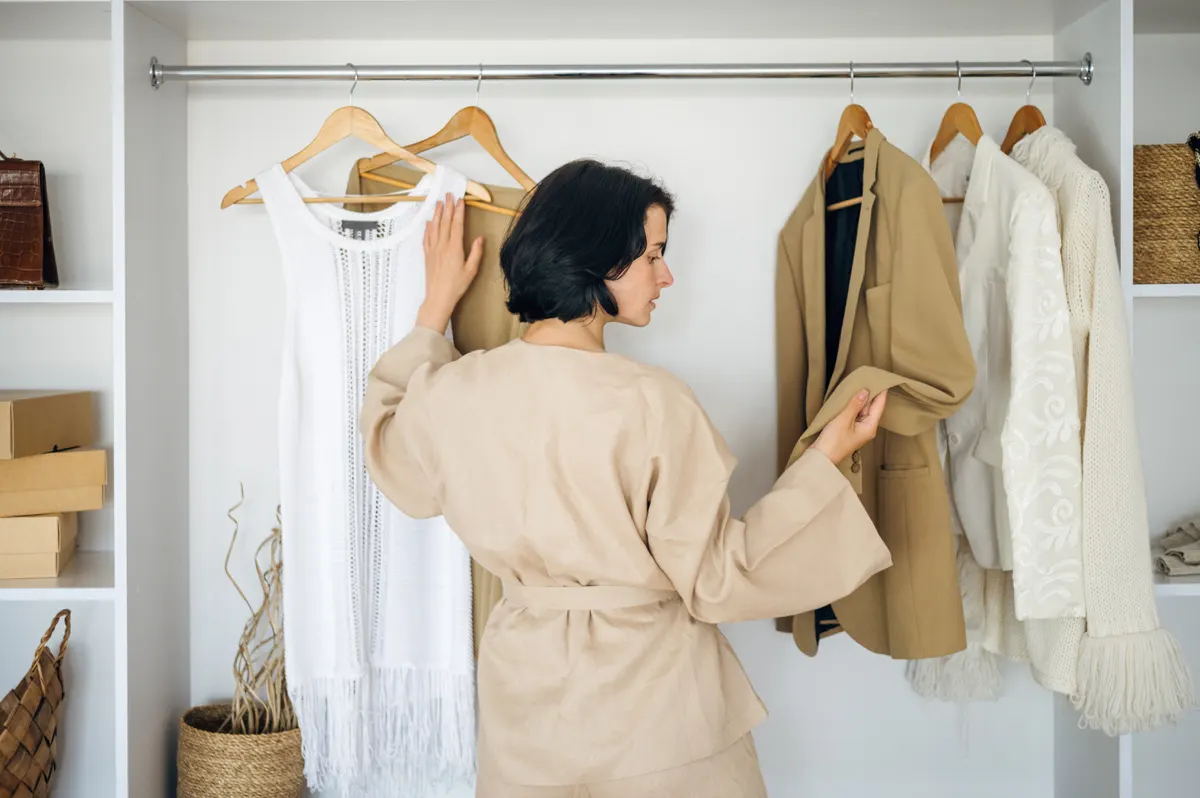 Woman browsing light neutral pieces on a wardrobe rail