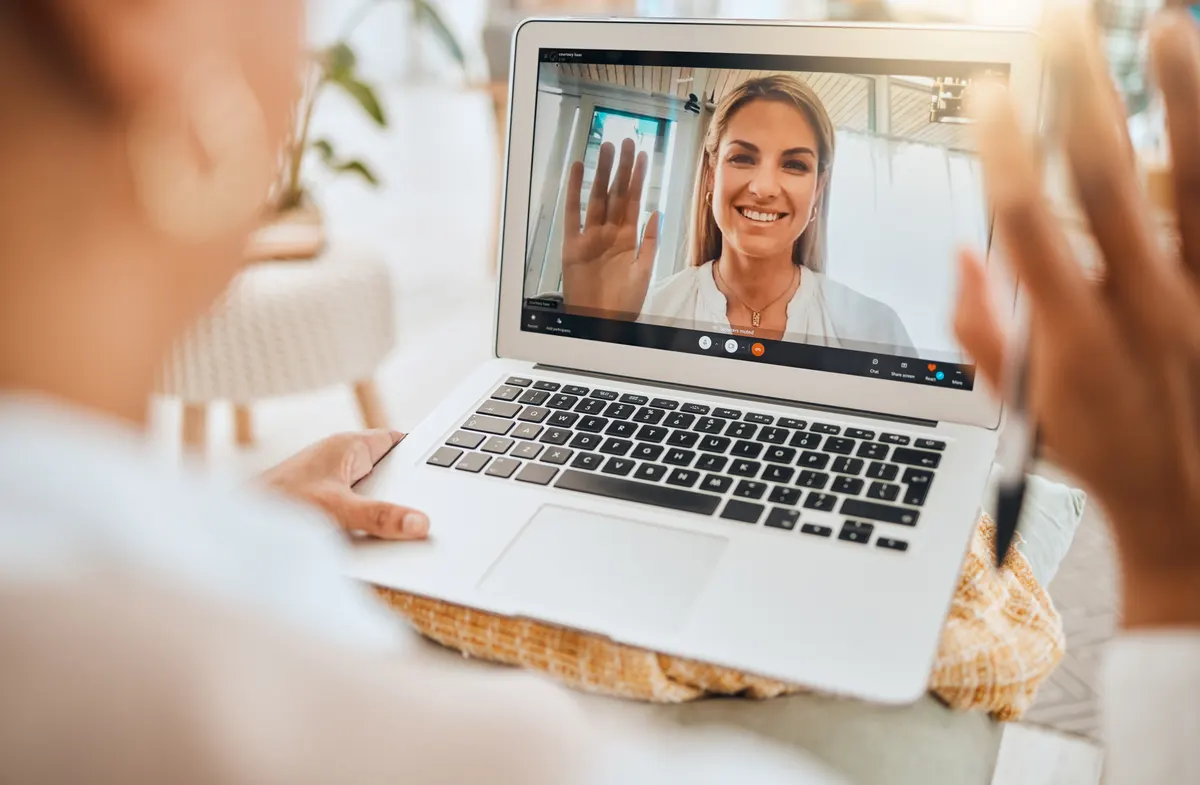 A video conversation on a laptop with clothing visible in the background