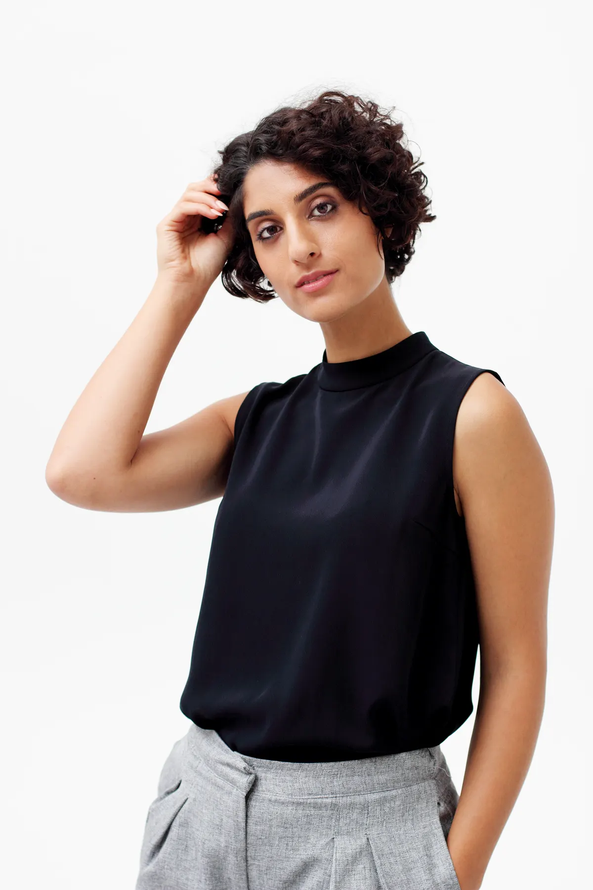 Woman pairing a sleeveless black top with pale trousers