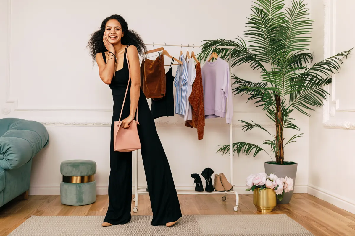Woman in a black trouser suit beside a clothes rail
