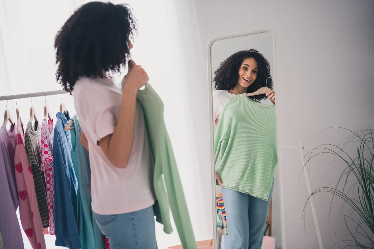 Woman trying a pastel outfit in front of a mirror
