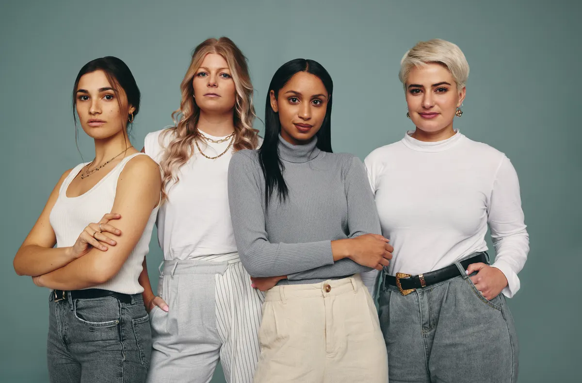 Four women combining neutral tops with muted trousers