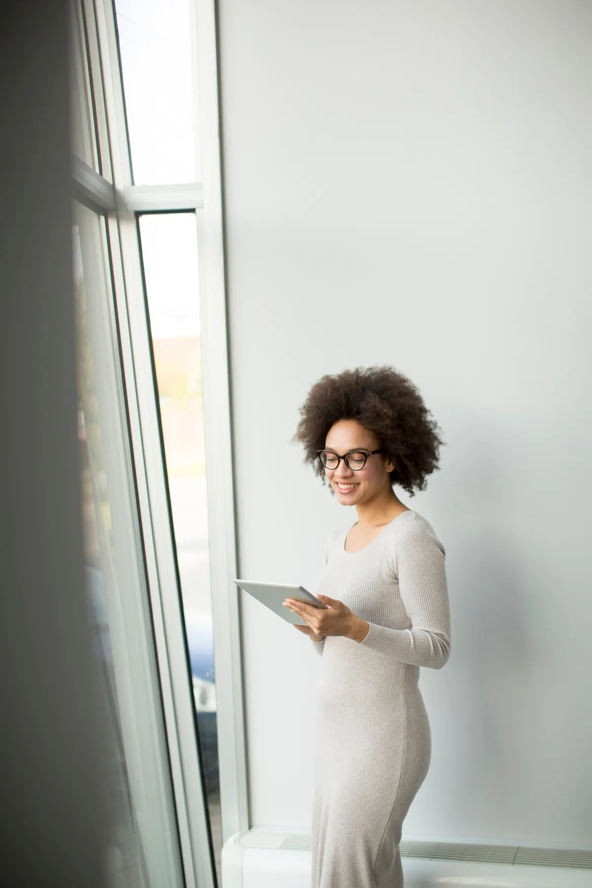 Woman wearing a relaxed all-white outfit beside a window