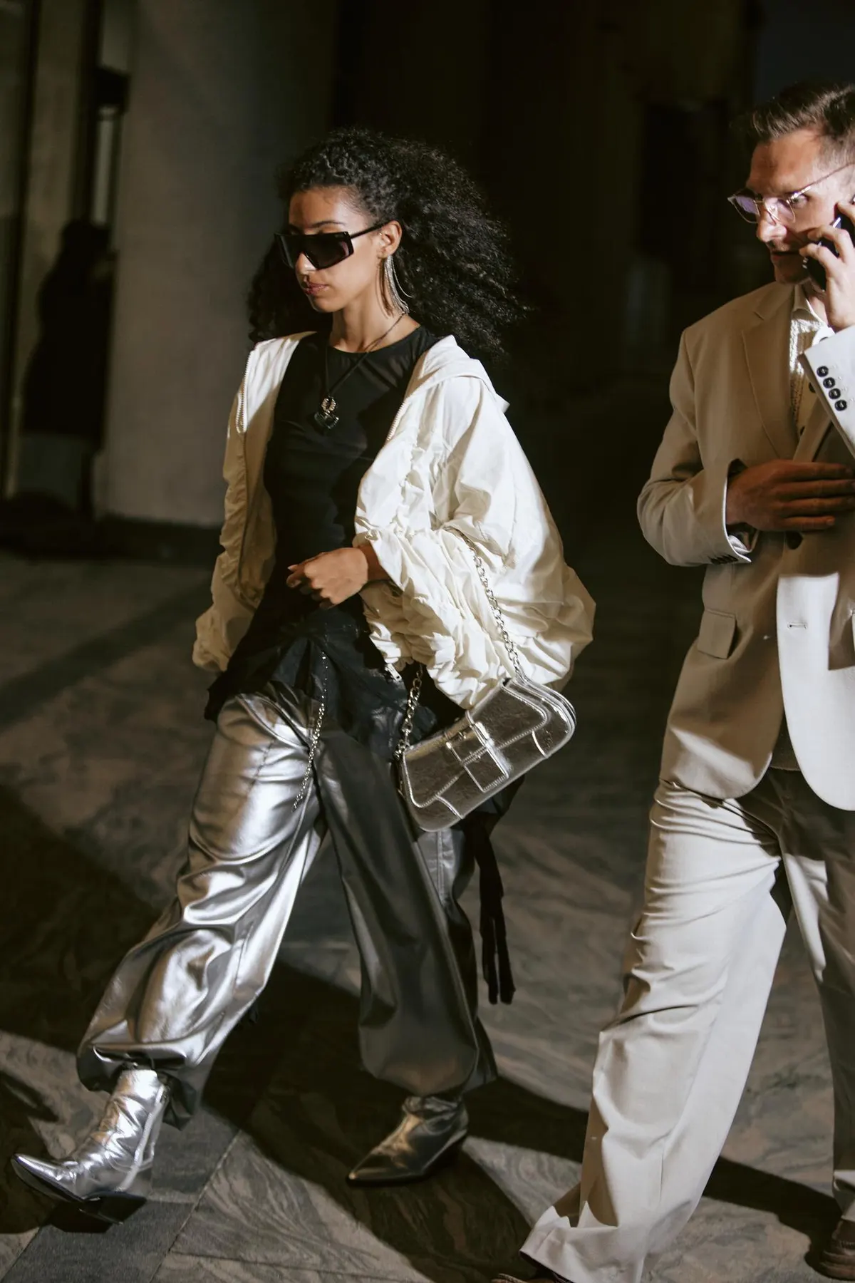 Street-style outfit combining a light blouse and metallic trousers