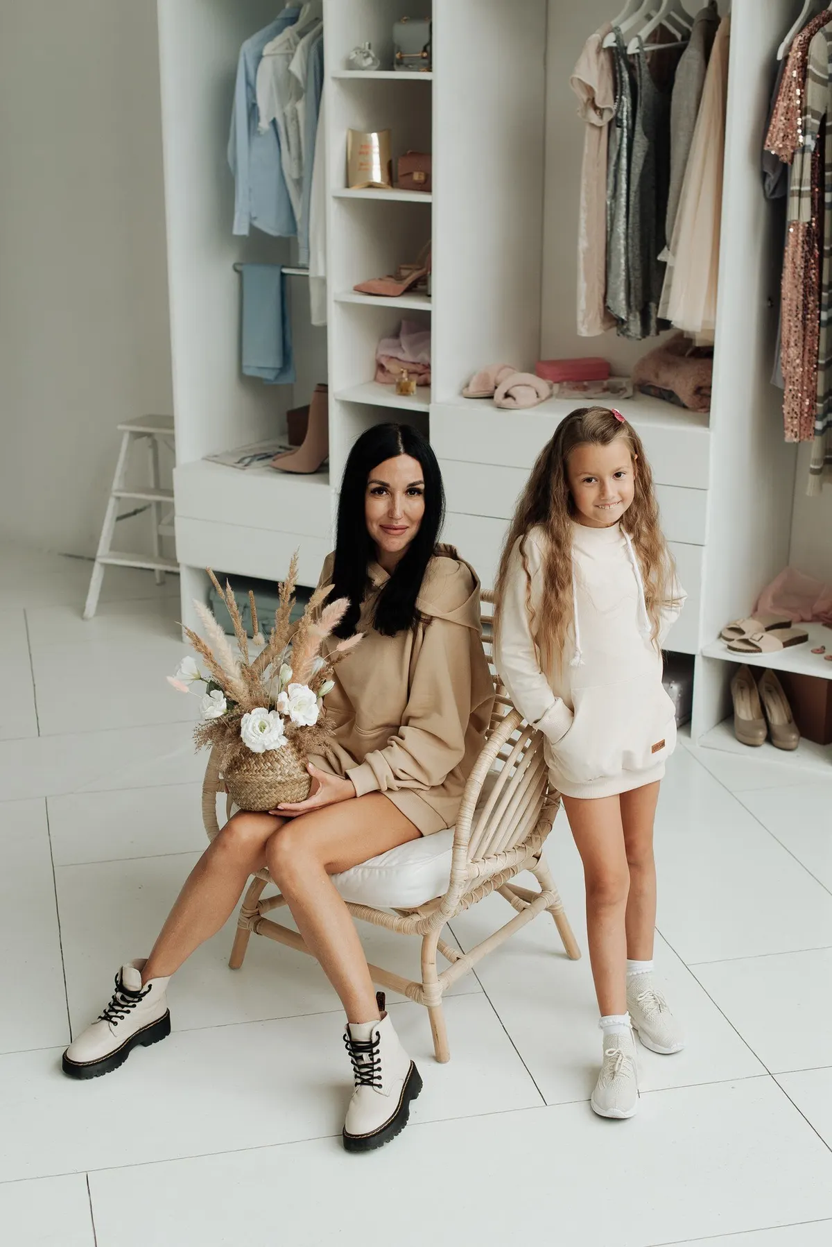 Two women sitting together in coordinated neutral outfits