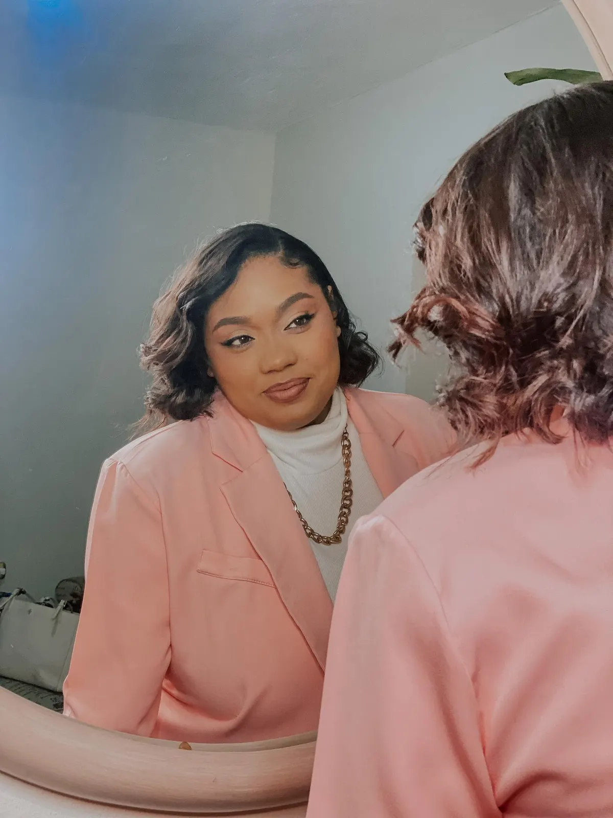 Woman trying a soft pink top in front of a mirror