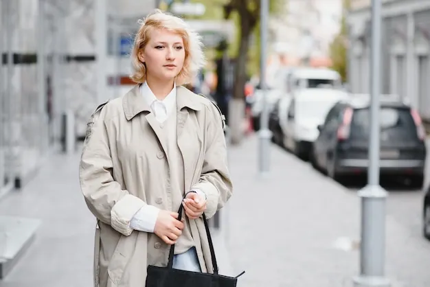 Woman wearing a belted light trench coat on a city street