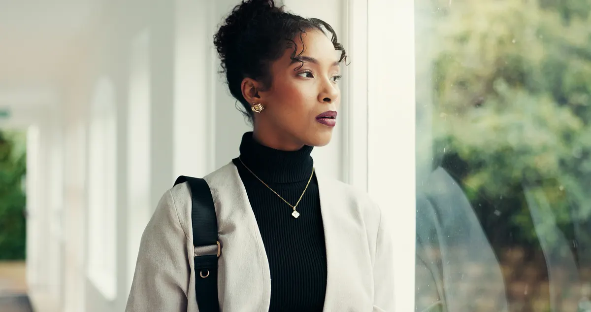 Woman layering a pale jacket over a black roll-neck top