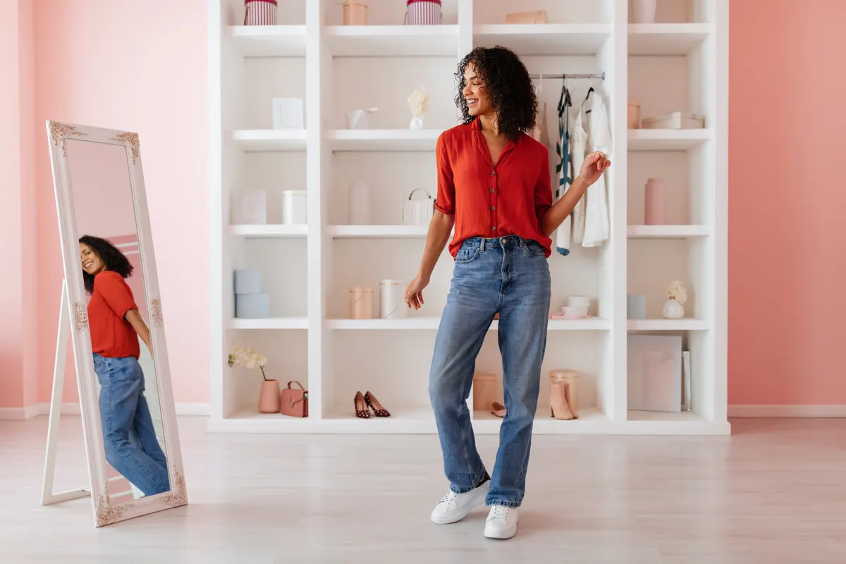 Woman choosing a red top from a white wardrobe