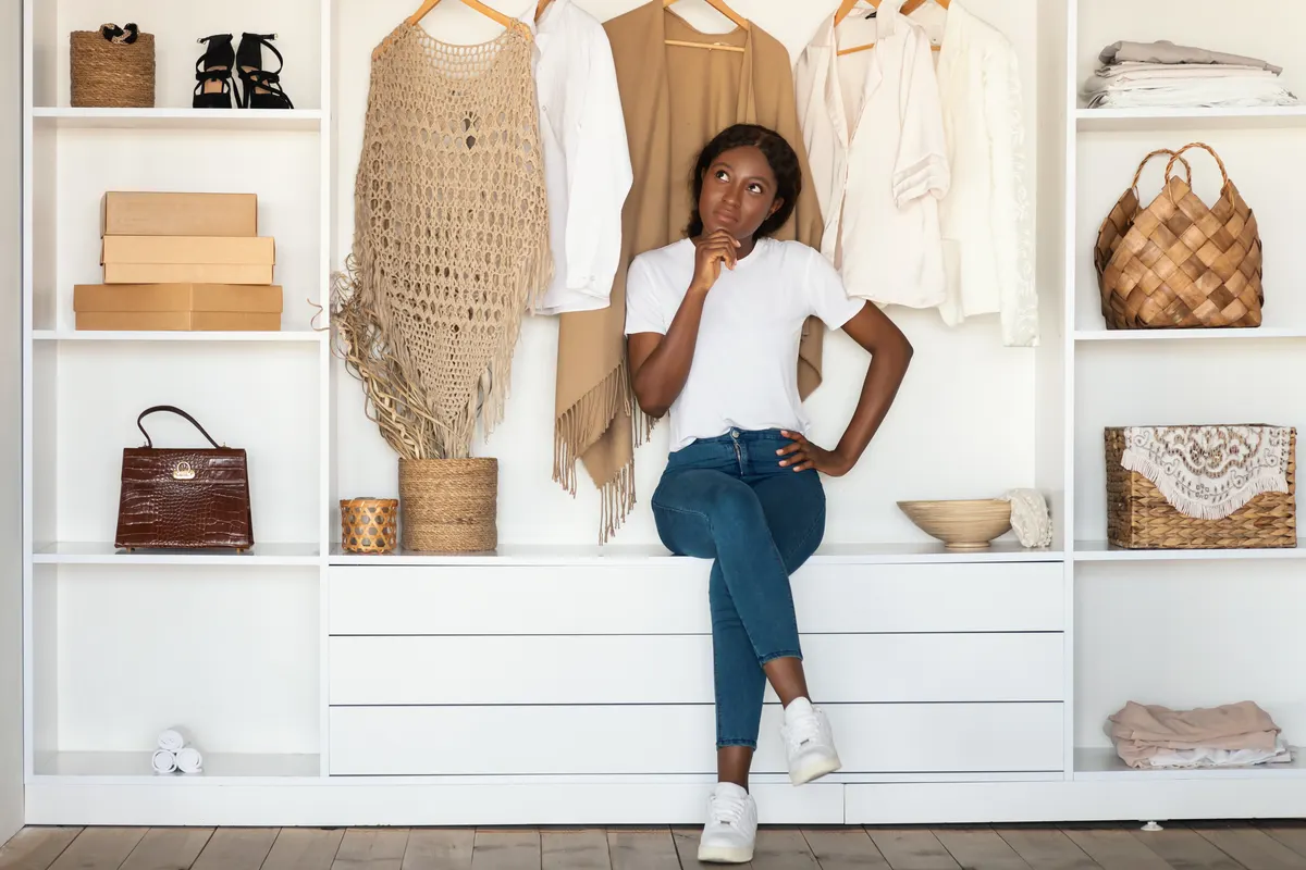 Woman seated beside an organised wardrobe and accessories