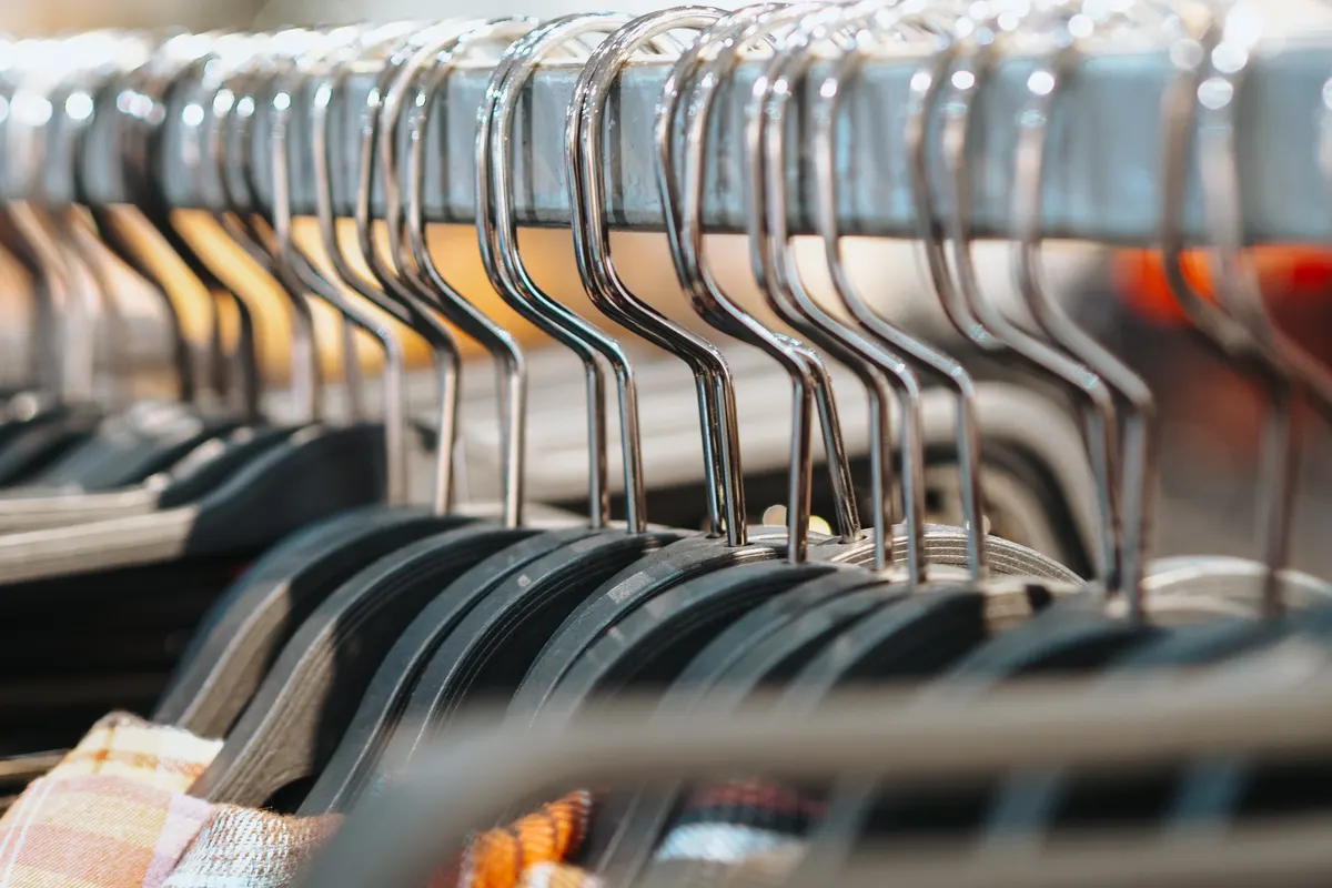 Clothes hanging from a neat row of metal hangers